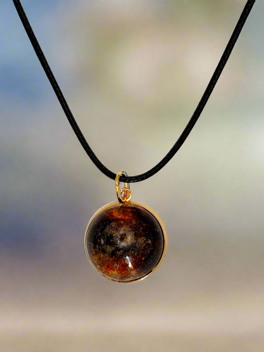 Necklace with a round pendant featuring a multicolored stone on a blurred background