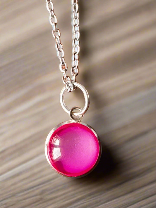 Necklace with a pink pendant on a wooden surface