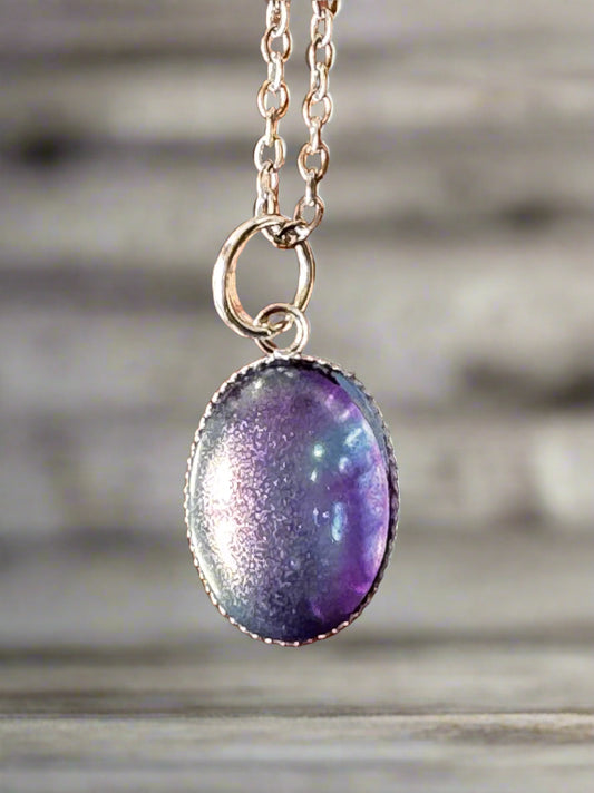 Purple pendant on a silver chain against a wooden background
